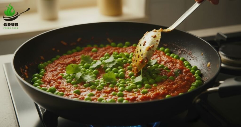 Cooked peas being mixed into masala gravy with coriander garnish.